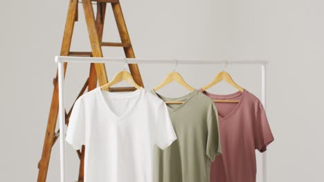 video of close up of white, beige and green t shirts hanging on white background