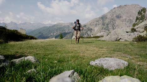 man with hiking poles arriving on the top of mountain with beautiful mountain range in background during summer day in italy