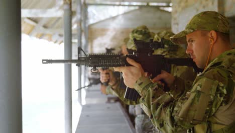 Side-view-of-mixed-race-military-soldiers-shooting-rifle-in-target-practice-during-training-4k