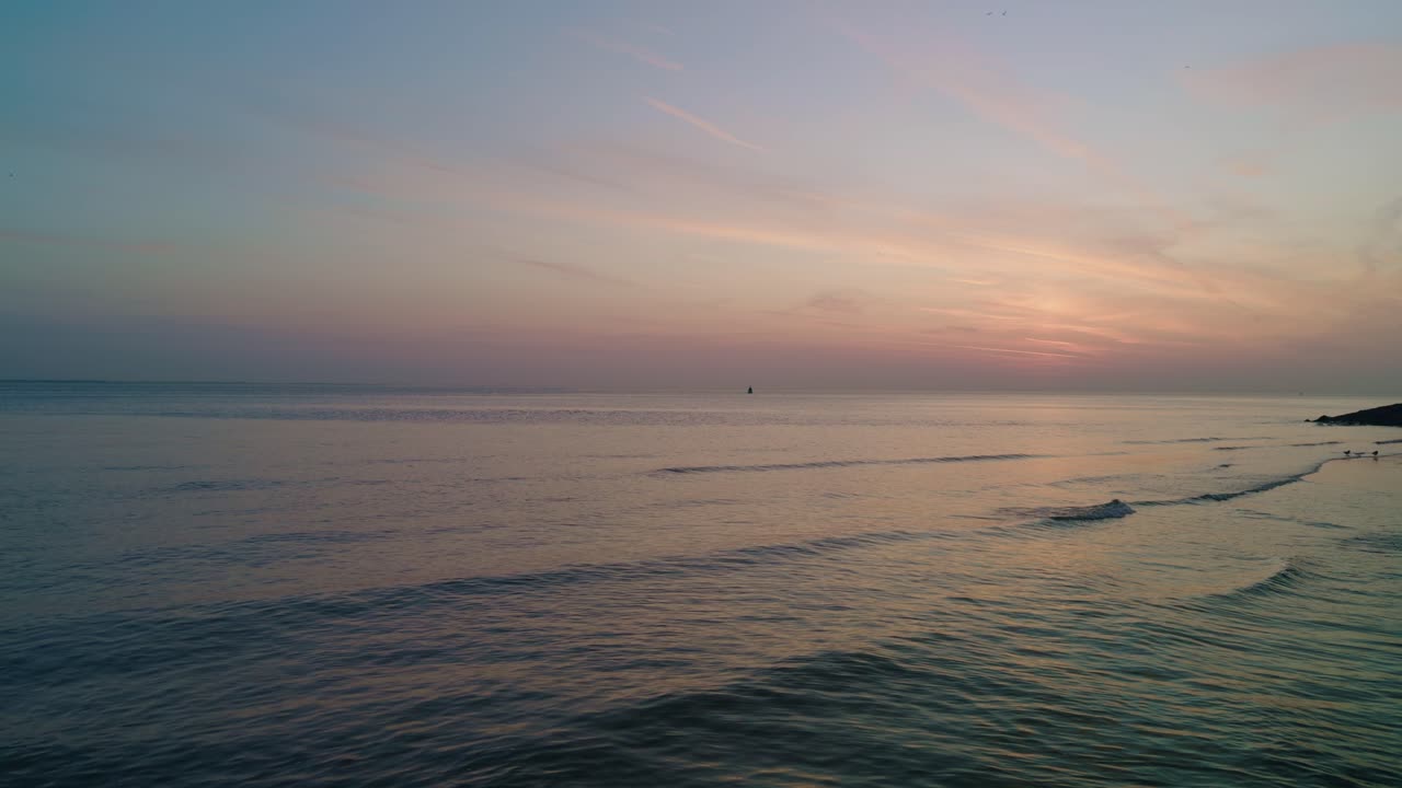 sunset on the seashore of North Sea Atlantic Ocean beach with calm waves and beautiful skyline horizon with evening afterglow. Netherlands, Europe