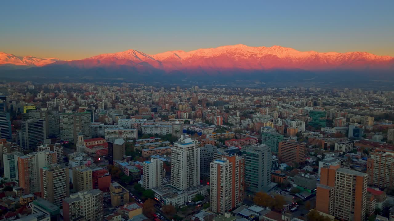 Sole che tramonta sulla Cordigliera delle Ande con il centro di Santiago in primo piano.