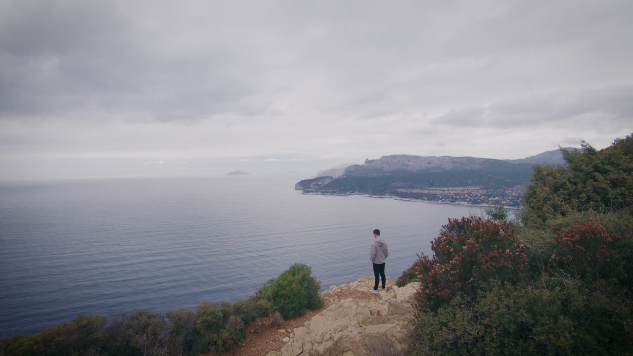 Man at the edge of cliff facing peaceful Mediterranean Sea, Marseille, France