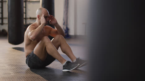 hombre calvo caucásico musculoso sin camisa haciendo ejercicio, haciendo abdominales