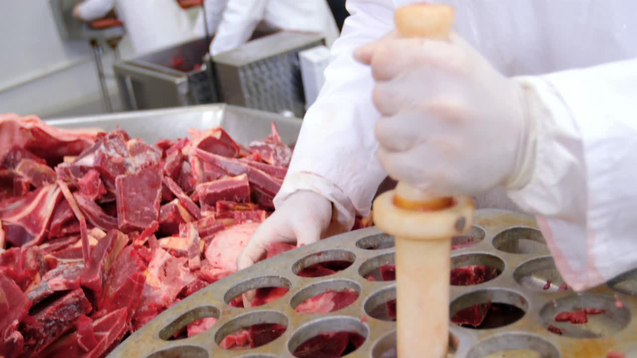 macellaio che mette la carne nella macchinetta per macinare