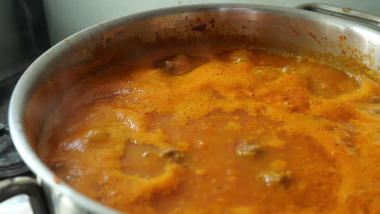 vista de cerca de la sopa de tomate está burbujeando en una sartén