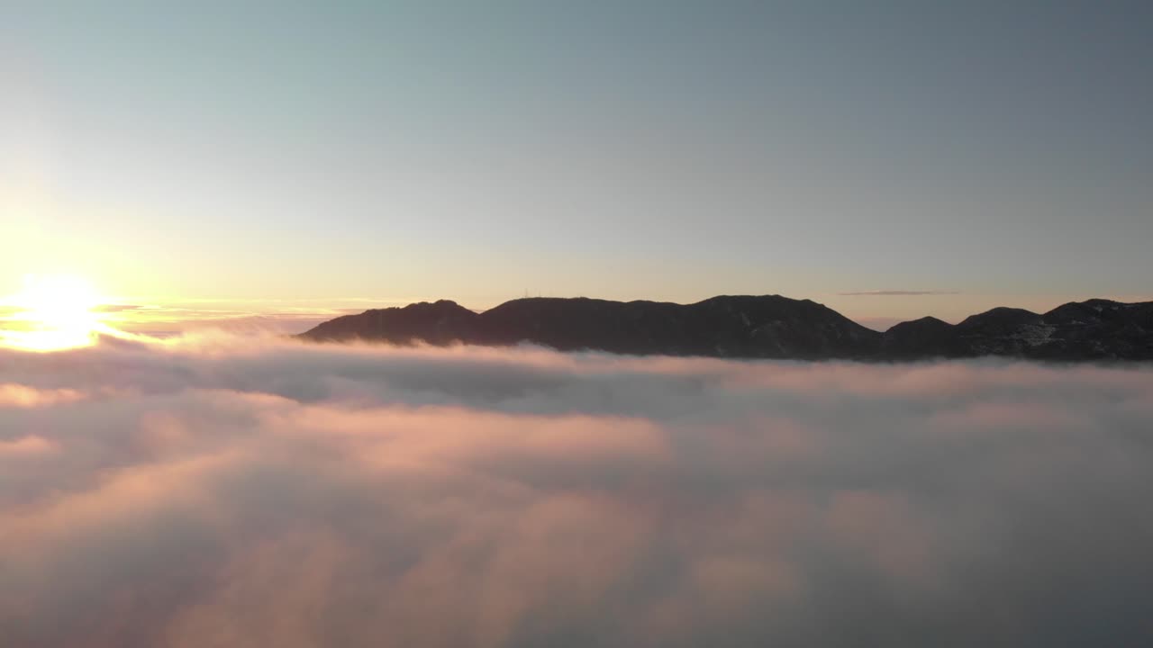 pan aéreo de montañas con salida del sol sobre valle brumoso, mar de nubes