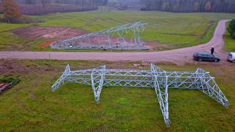 drone flying over a high-voltage tower on the ground ready for lifting and installation