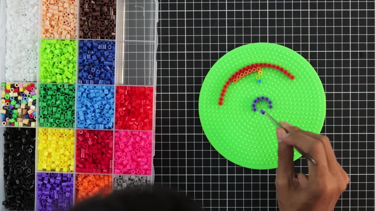 cuentas coloridas en pegboard para la actividad de artesanía, mano creando un patrón, lapso de tiempo