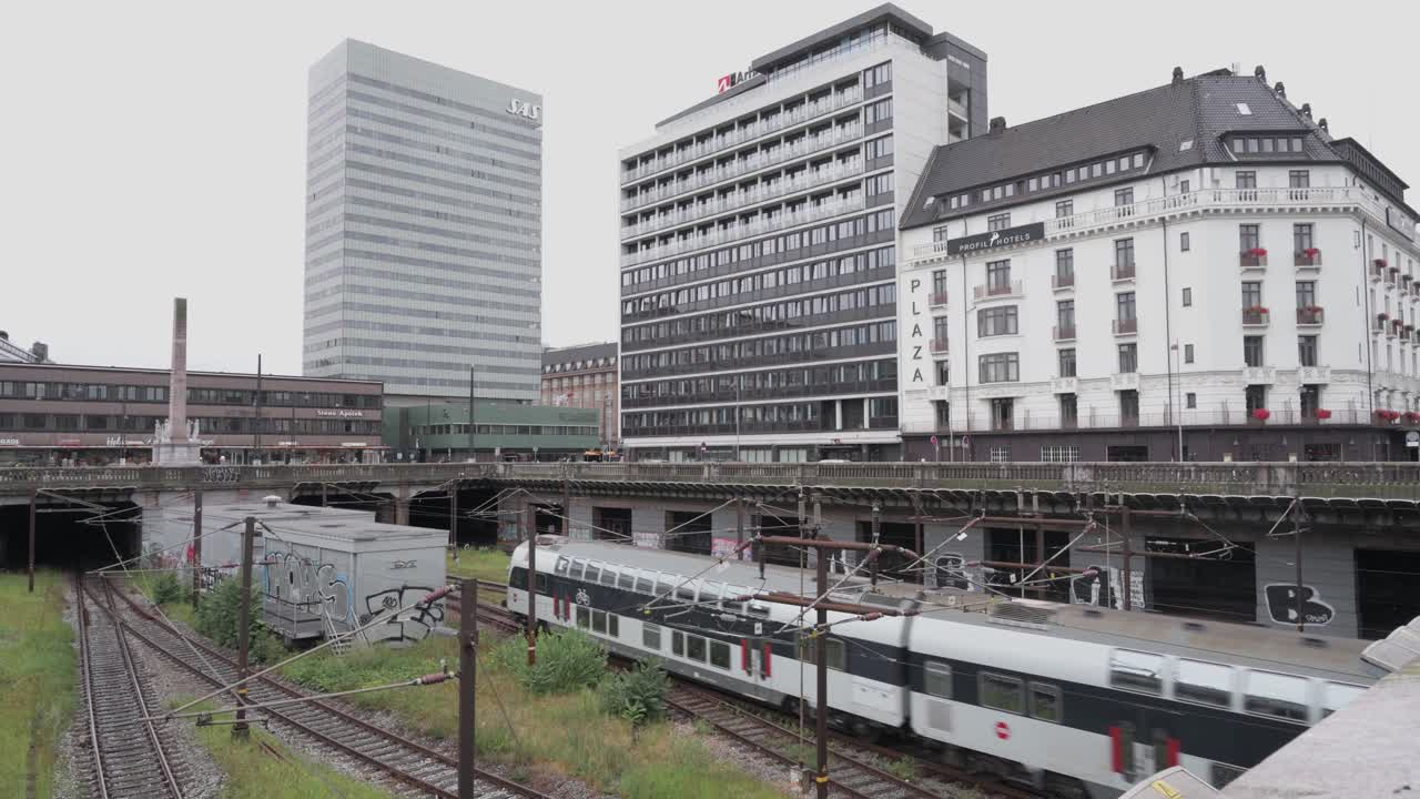 Red passenger plane pulling into the station in Copenhagen Denmark, with building in the bacground