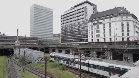 red passenger plane pulling into the station in copenhagen denmark, with building in the bacground