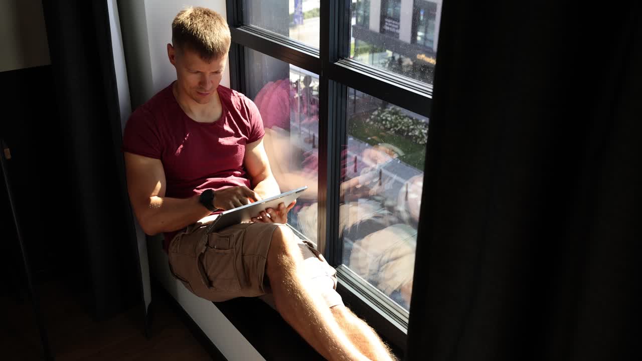 Man sitting by window using a tablet