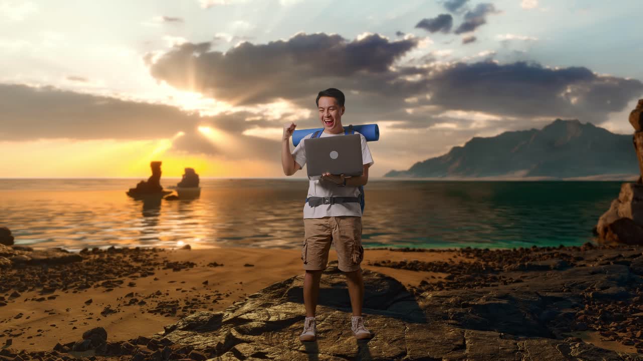 Pendaki Pria Asia dengan Seluruh Badan dengan Ransel Gunung Sedang Melihat Laptop dan Meneriakkan Gol Merayakan Kesuksesan di Pantai