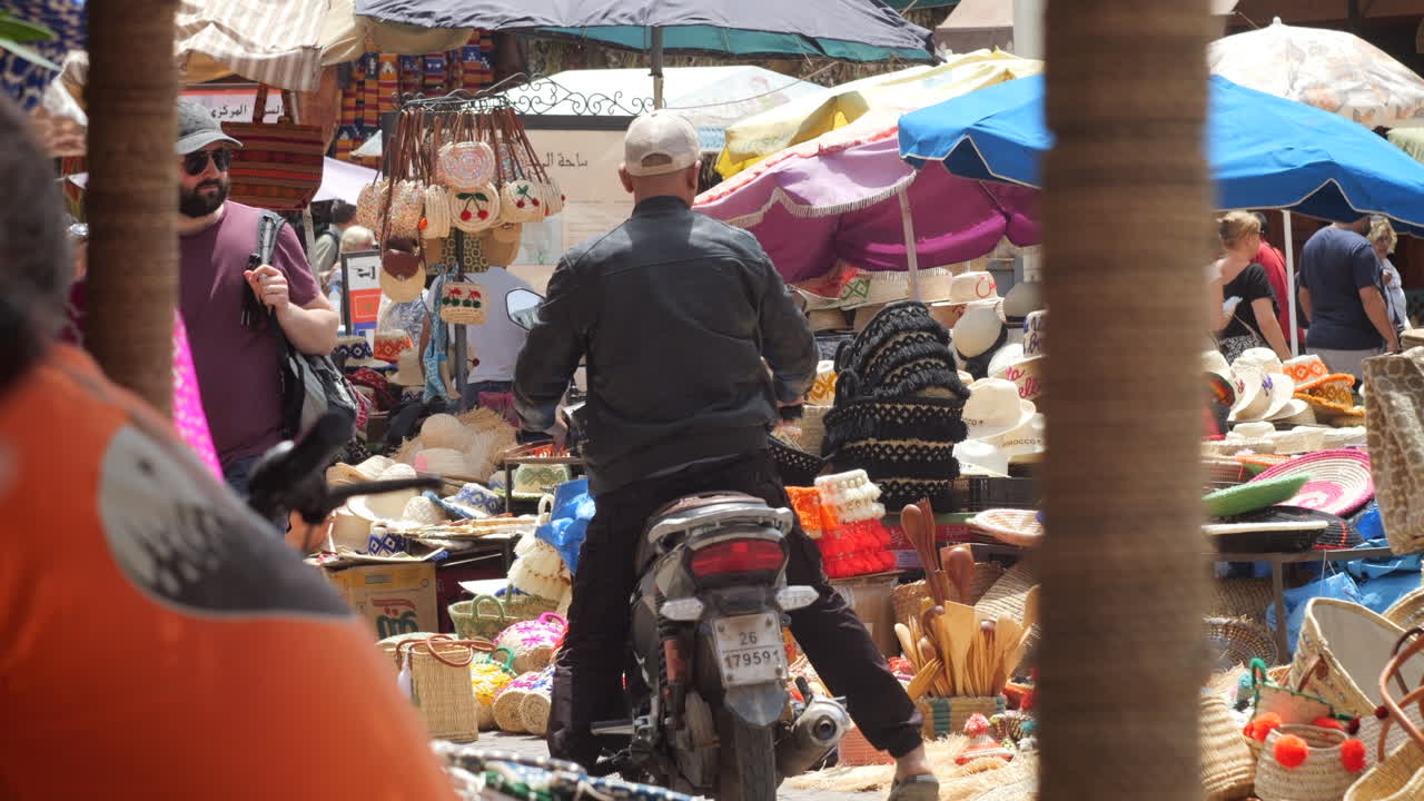 A Man on a Scooter Navigates a Bustling Moroccan Outdoor Market