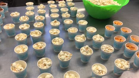 refrigerios populares para niños como pretzels, palomitas de maíz y peces dorados colocados en tazas pequeñas para que los niños los agarren y se vayan fácilmente