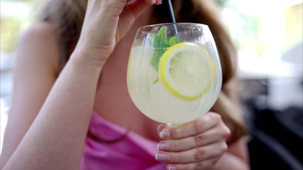 Donna che beve un bicchiere di limonata con menta e ghiaccio, slow motion