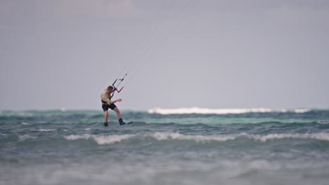 Medium-panning-shot-of-a-kitebaorder-jumping-and-doing-tricks,-slow-motion