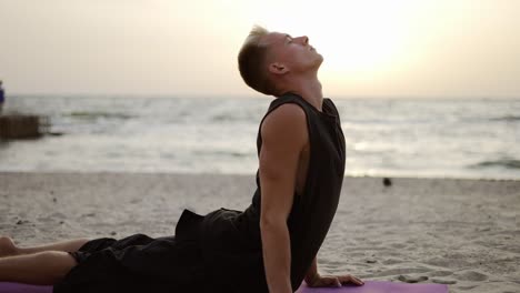 a young man practices yoga and meditates on a sports mat while lying down at dawn. performing a specific exercise. meditation