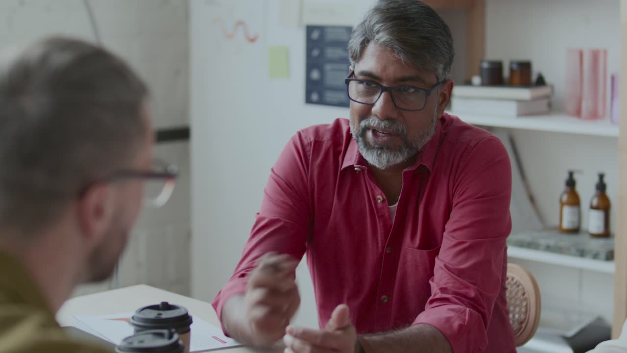 Middle-Aged Indian Businessman Having Talk with Colleagues in Office