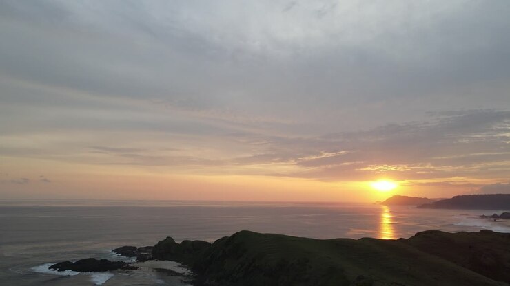 Tramonto dorato su oceano sereno e verdi scogliere costiere