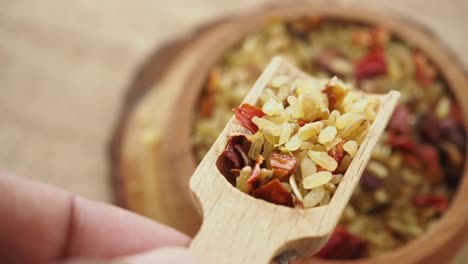 scooping mixed spices from a wooden bowl