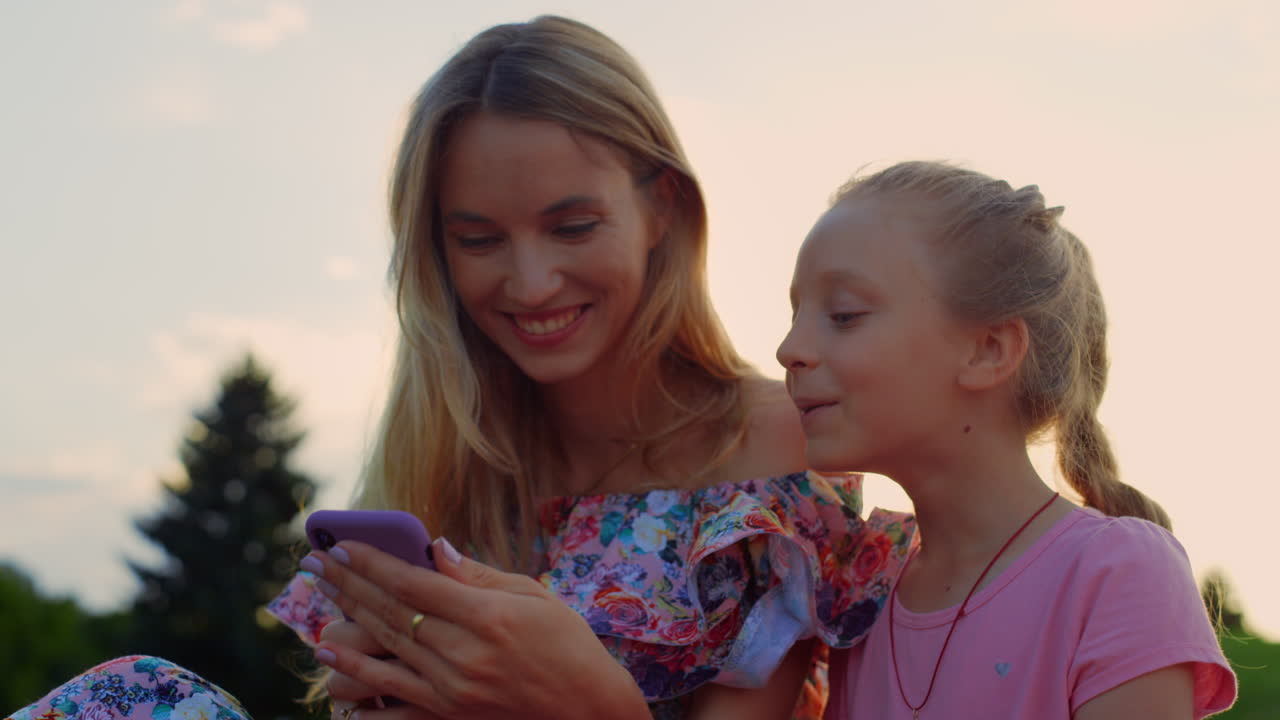행복한 가족이 공원에서 웃고, 여자와 소녀가 야외에서 즐기고.