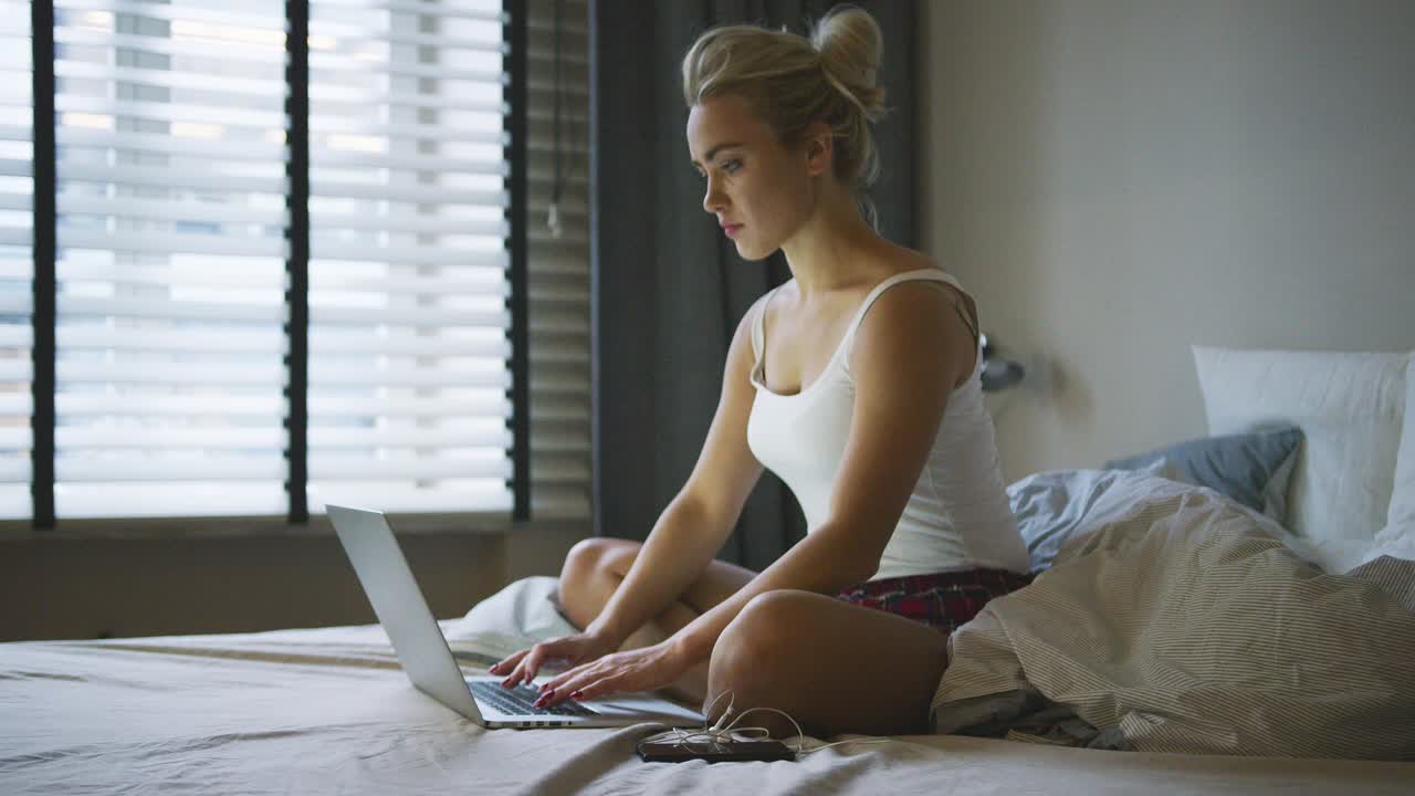mujer usando laptop en la cama y pensando
