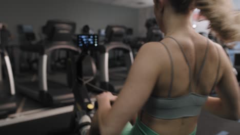 vista trasera de una mujer haciendo ejercicio en una máquina de remo.