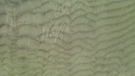 aerial: close up of sea bottom with waves on the surface of the sea