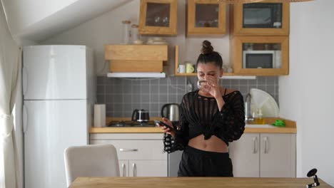 young woman using phone in kitchen