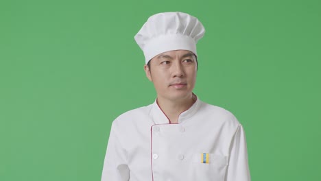 el chef asiático caminando y mirando a su alrededor en el estudio de fondo de la pantalla verde