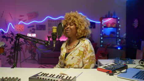 mujer cantando en un micrófono en un estudio de grabación