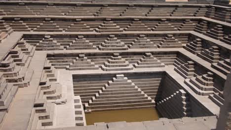 Intricate-Stepped-Tiers-Surrounding-The-Stepped-Tank-On-A-Sunny-Day-In-Karnataka,-Hampi,-India