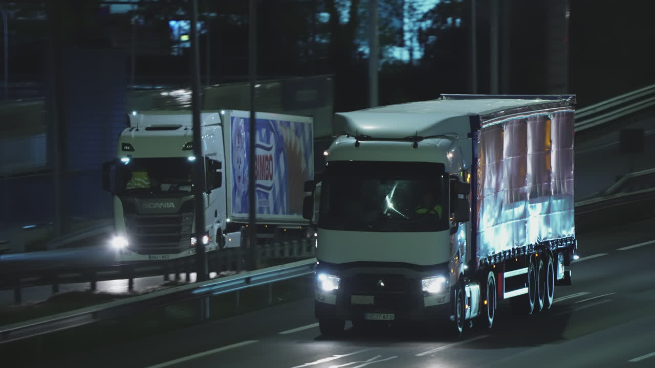 Camion commerciali e auto che viaggiano su un'autostrada di notte