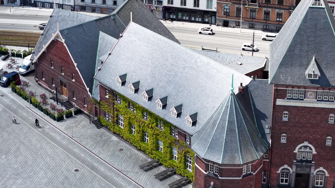 Drone aerial footage of a historic red brick building in downtown Aarhus, Denmark, captured on a sunny day