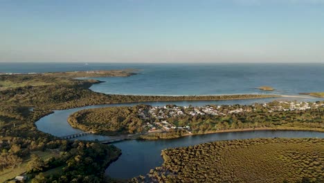 aerial establishing pullback above minnamurra, australia, featuring coastal village with sweeping ocean and town views