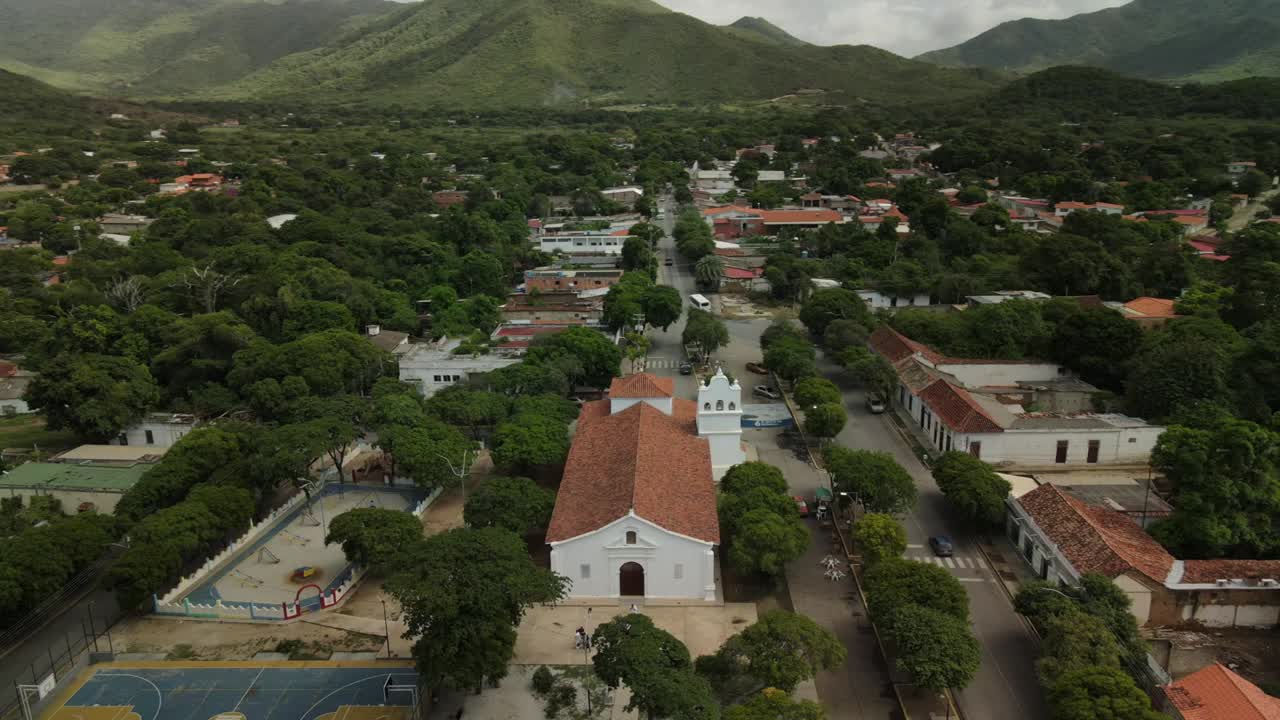 Aerial pan of Santa Ana Church in Isla de Margarita, Venezuela, surrounded by trees and mountains