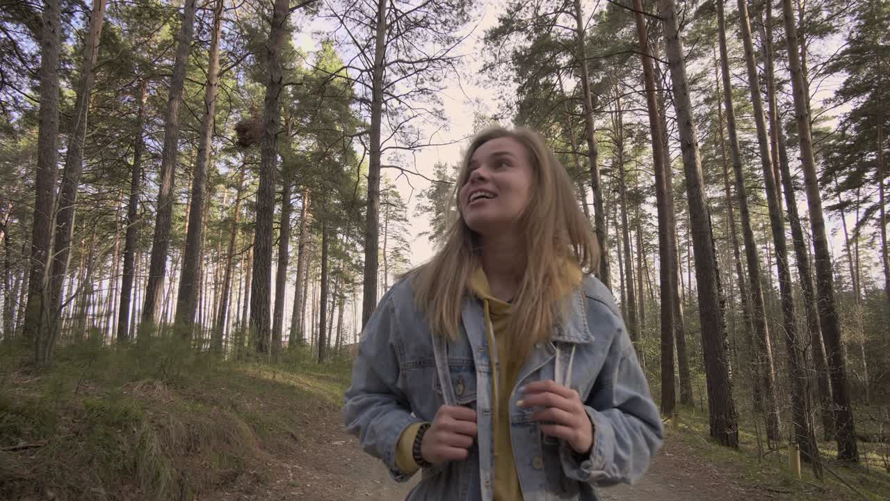 joven sonriente caminando en el bosque de otoño