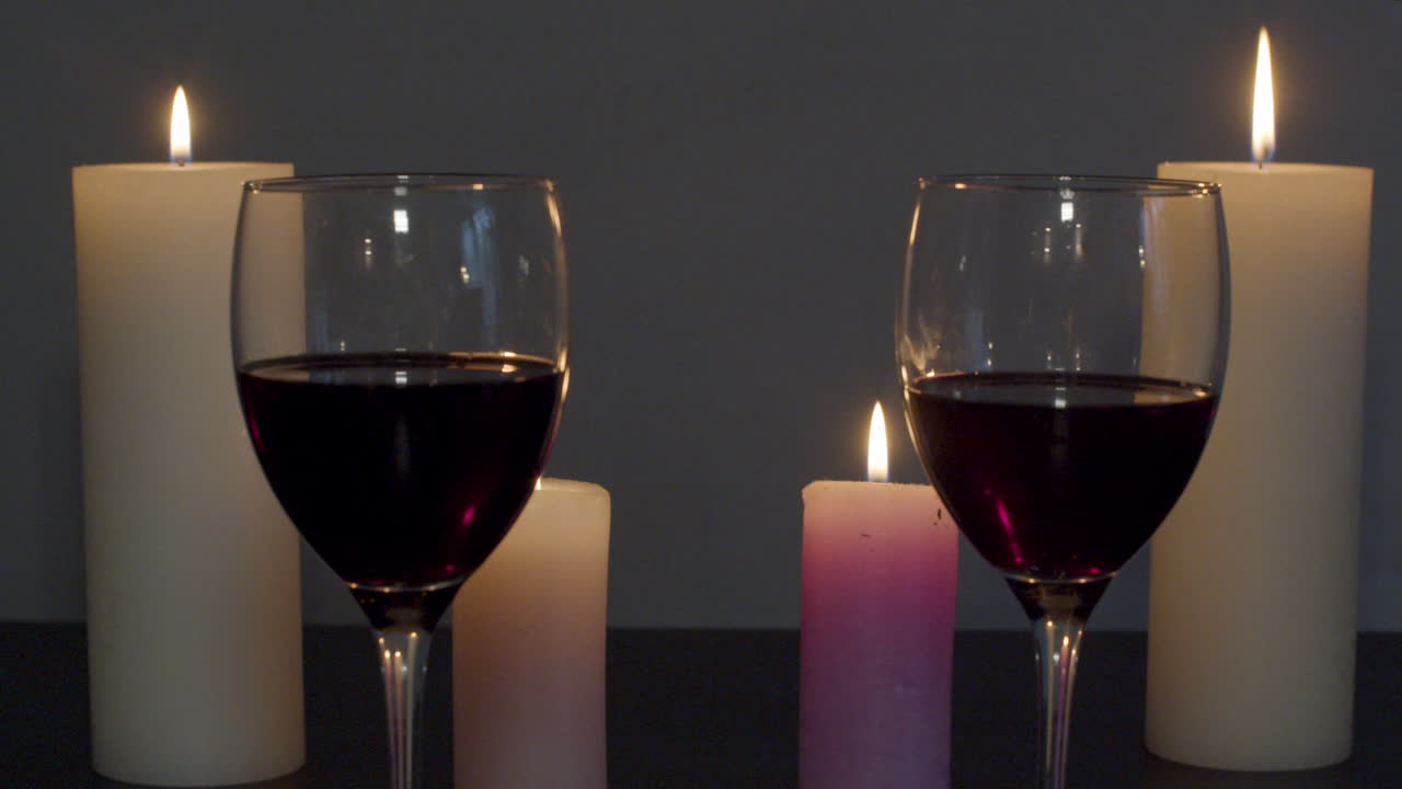 Dolly out of two glasses of wine on a candle lit table