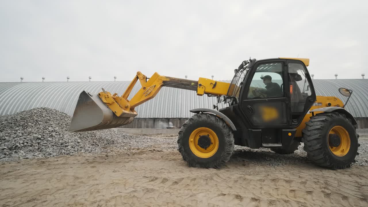 Tractor moves rubble to truck. Excavator-loader rakes rubble from pile at construction site and loads dump truck. Clearing site