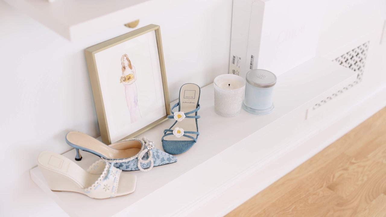 a fashion inspired shelf decorated with a piece of artwork and designer shoes next to two candles