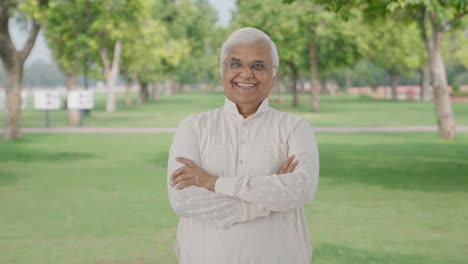 Happy-Indian-old-man-standing-crossed-hands-in-park