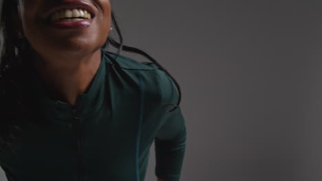 close up studio shot of female athlete wearing tracksuit training out of breath but smiling and recovering after exercise