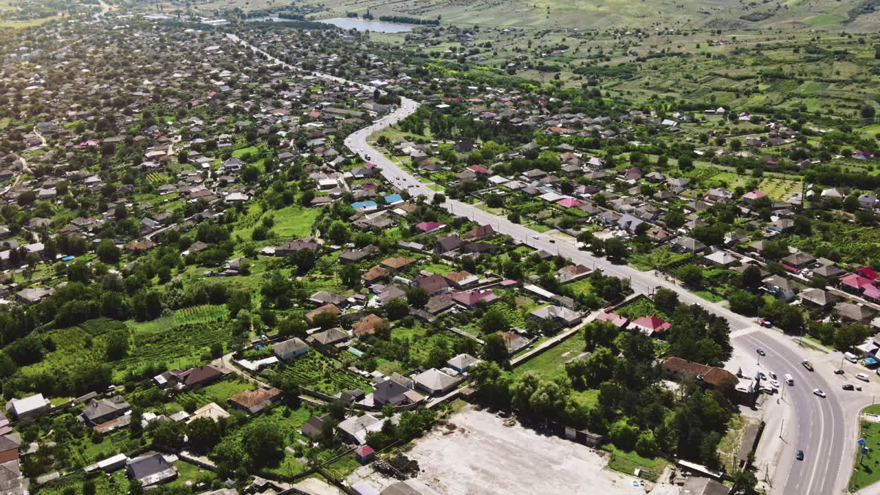 Aerial drone view of a village and road with cars. Greenery, multiple houses in Moldova
