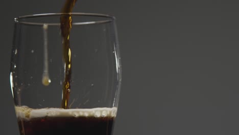 una pinta de cerveza negra irlandesa se vierte en un vaso contra el fondo negro del estudio para celebrar el día de san patricio 4