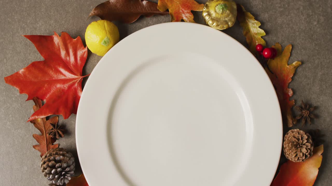 video de un plato con hojas de otoño y decoración sobre una superficie gris