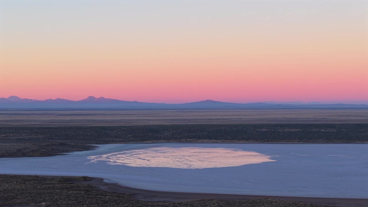 Salinas del Diamante i Mendoza, Argentina, viser en saltsø, ørkenbassin og fjerne Andesbjerge under pastelfarvede skumringsfarver, drone sidelæns glidning.