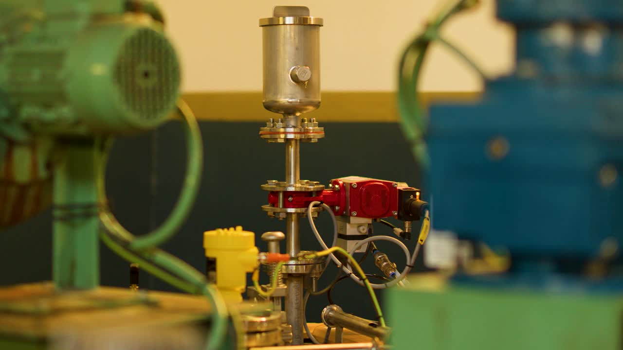 Industrial electric motors and valves in distillery factory, slow lateral camera pan, warm lighting