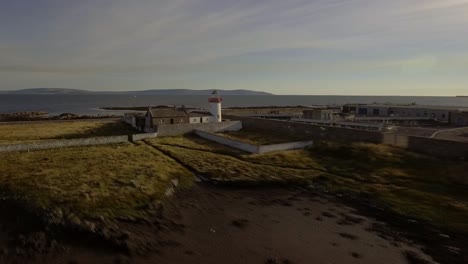 Cinematic-aerial-shot-of-abandoned-lighthouse-beside-a-wastewater-treatment-plant