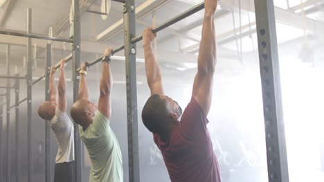 Entrenamiento-De-Clases-De-Fitness-De-Grupos-Masculinos-Diversos-En-El-Gimnasio-Haciendo-Dominadas-En-Barras,-En-Cámara-Lenta