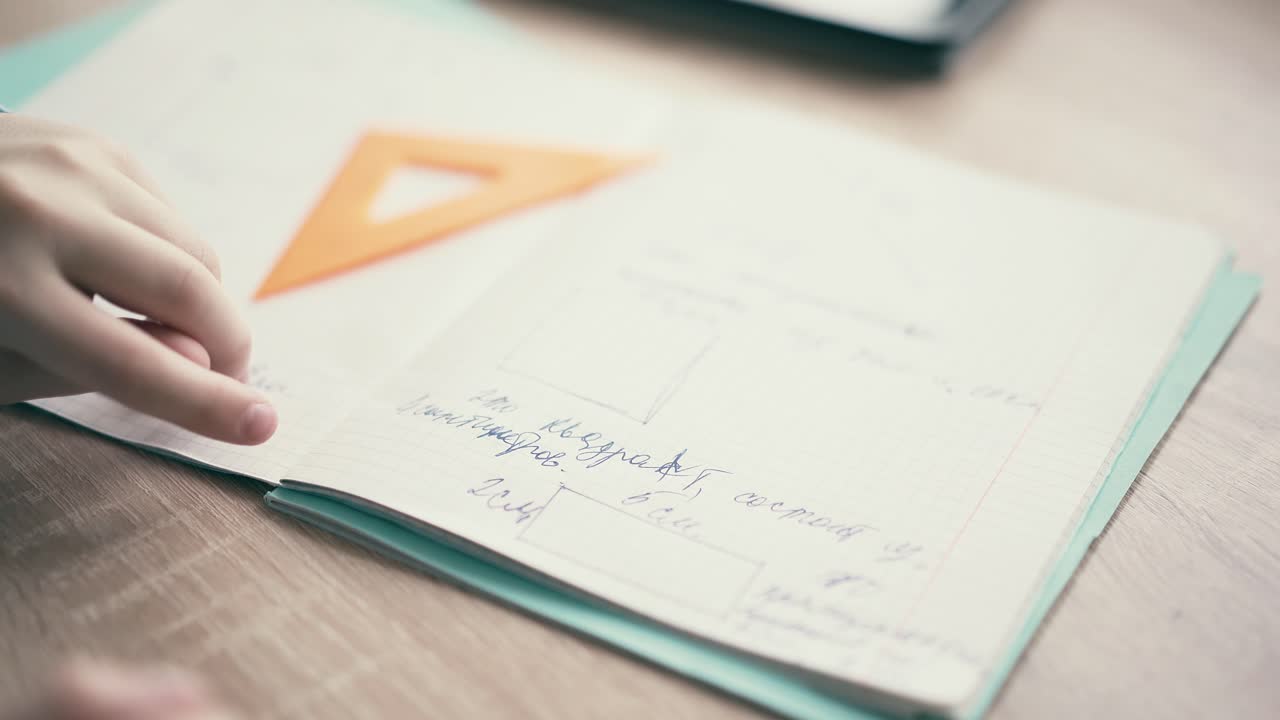 cu niño sentarse en los auriculares y hacer la tarea de la escuela pasa por la página en el cuaderno